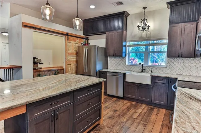 a kitchen with kitchen island granite countertop stainless steel appliances a sink stove and refrigerator