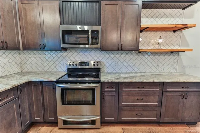 a kitchen with granite countertop wood cabinets and stainless steel appliances