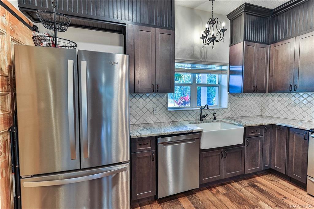 110 North Rooks Avenue Inverness, FL 34453 - Photo 6 of 34 a kitchen with stainless steel appliances granite countertop a refrigerator a sink dishwasher and wooden cabinets with wooden floor