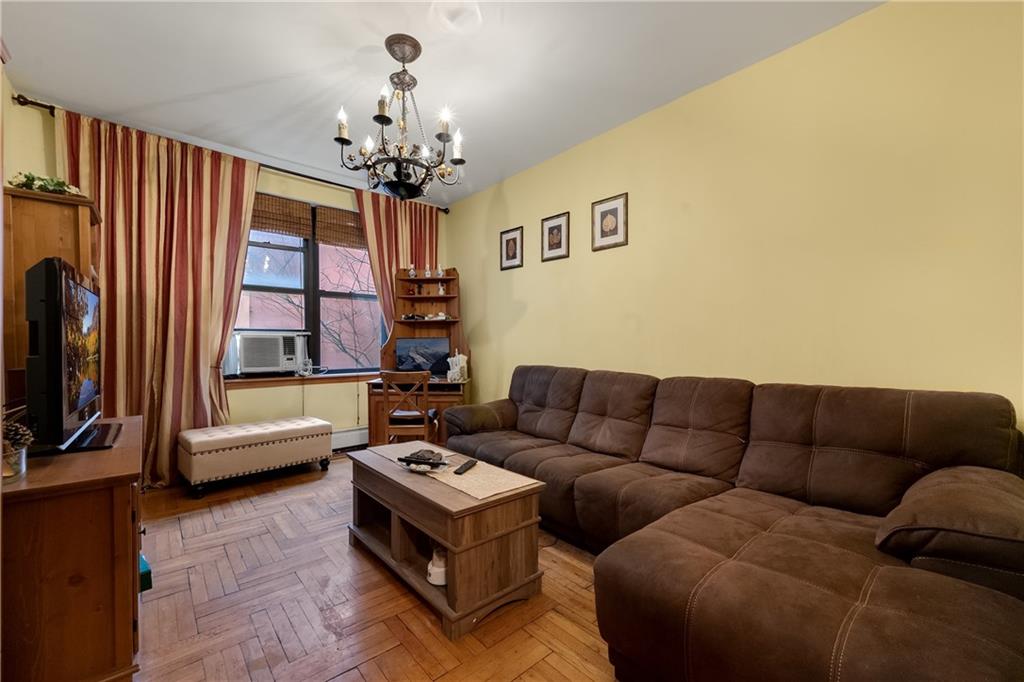 3045 Ocean Parkway, Unit 2D Brooklyn, NY 11235 - Photo 3 of 10 a living room with furniture a chandelier and a flat screen tv