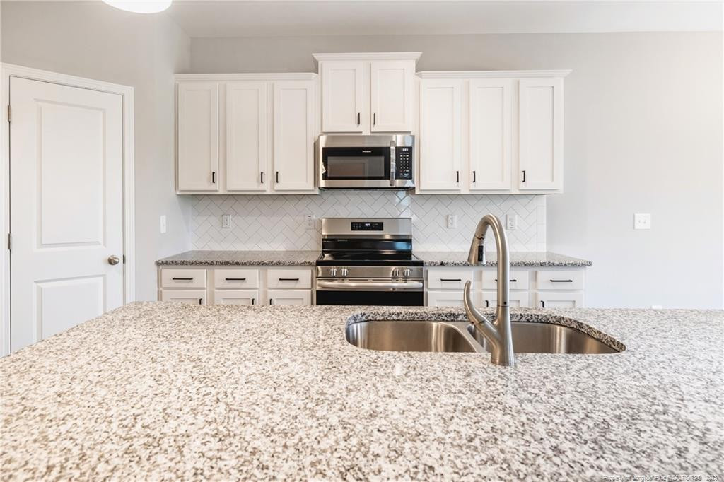 260 Carolina Church Road St. Pauls, NC 28384 - Photo 25 of 32 a kitchen with granite countertop a sink a stove and a microwave