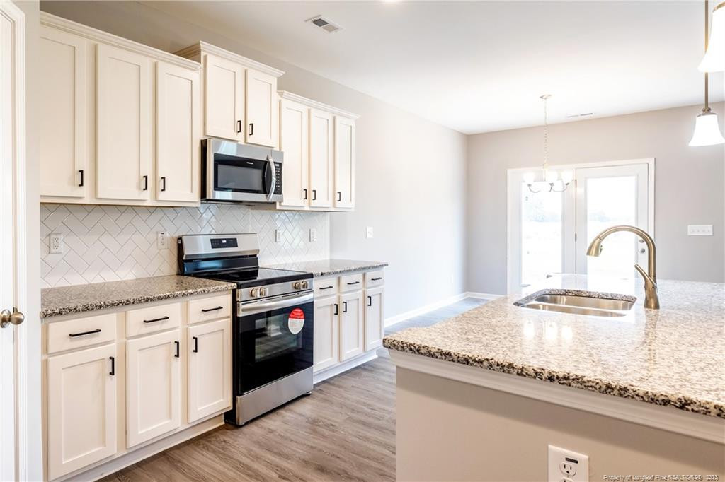 260 Carolina Church Road St. Pauls, NC 28384 - Photo 26 of 32 a kitchen with stainless steel appliances granite countertop a stove a sink and white cabinets