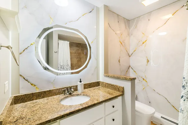 a bathroom with a granite countertop sink a toilet and a mirror