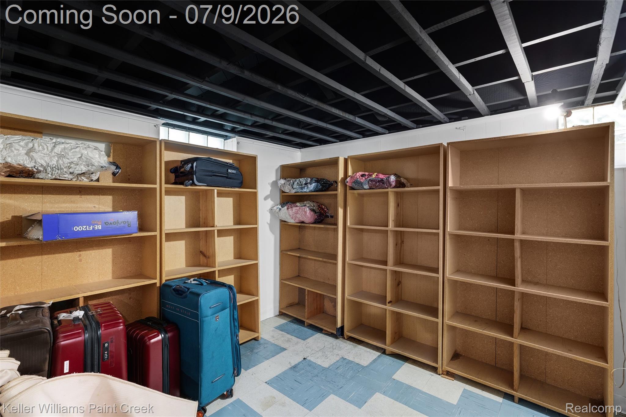 2731 Crooks Road Royal Oak, MI 48073 - Photo 26 of 34 Storage area featuring multiple freestanding wood-finish shelving units, an exposed black ceiling, and a light-colored floor with blue geometric accents
