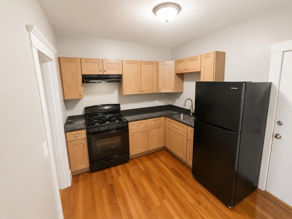 196 Washington Street, Unit 2 Lynn, MA 01902 - Photo 1 of 4 a kitchen with a refrigerator stove and wooden cabinets