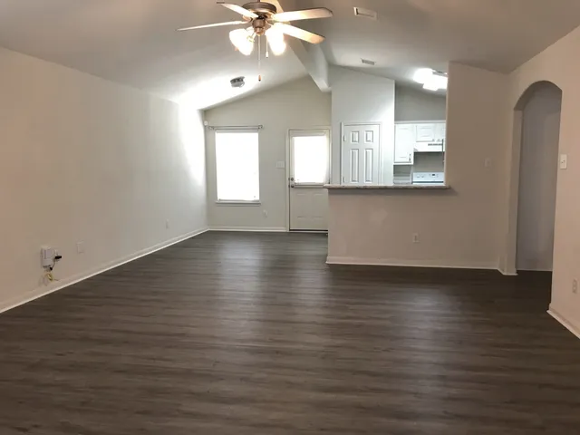 an empty room with wooden floor and windows