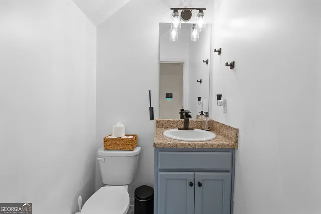 a bathroom with a granite countertop sink toilet and mirror