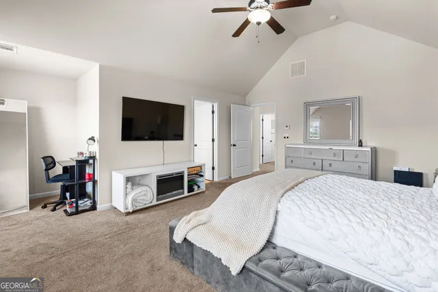 a spacious bedroom with a bed and a flat screen tv