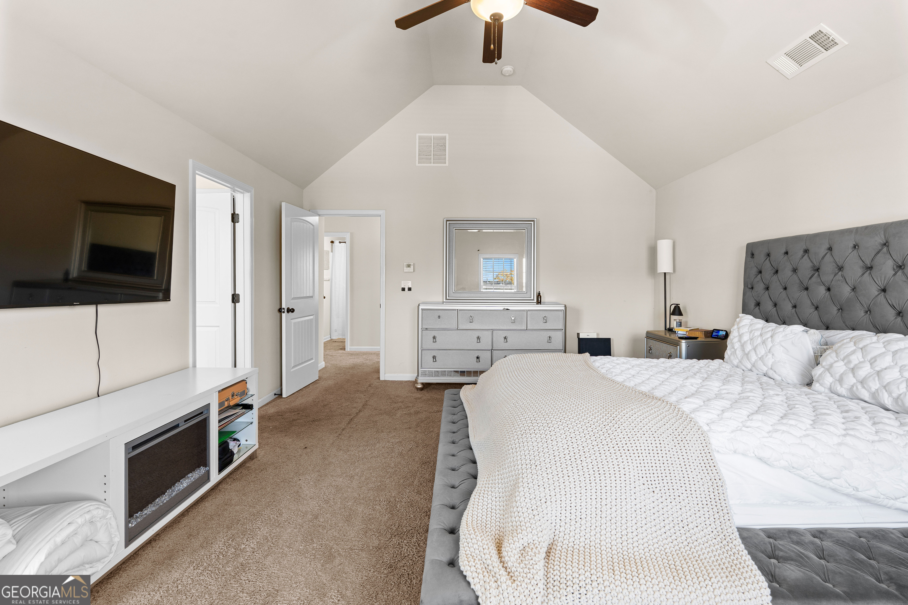 112 Truman Court Jackson, GA 30233 - Photo 32 of 41 a spacious bedroom with a bed a mirror on dresser and a flat screen tv