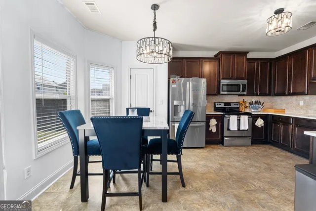 a dining room with wooden floor a chandelier a wooden table and chairs