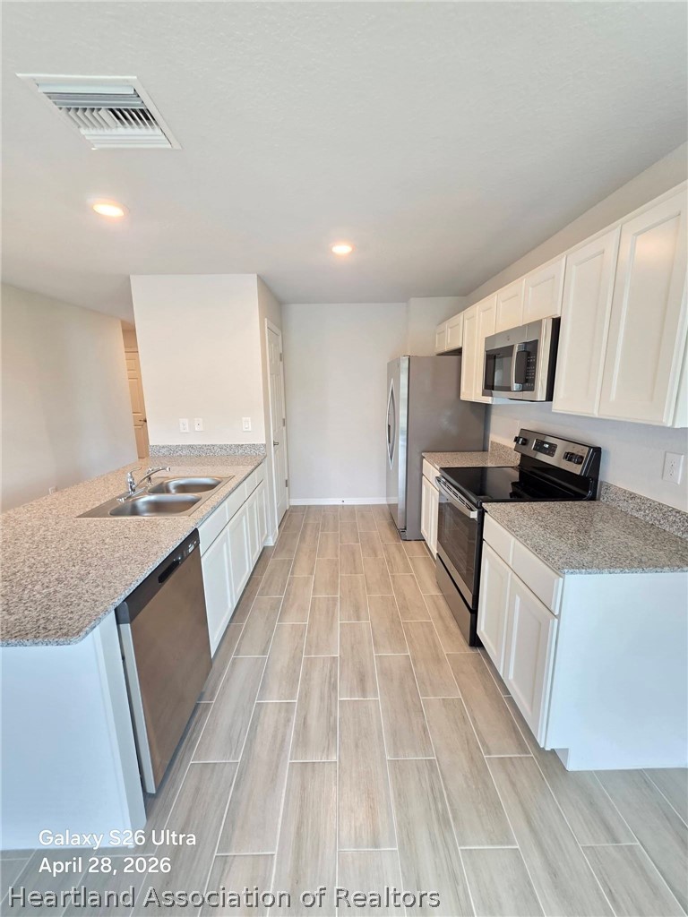 1613 Marble Street Sebring, FL 33870 - Photo 3 of 20 a large kitchen with stainless steel appliances granite countertop a stove a sink and a microwave