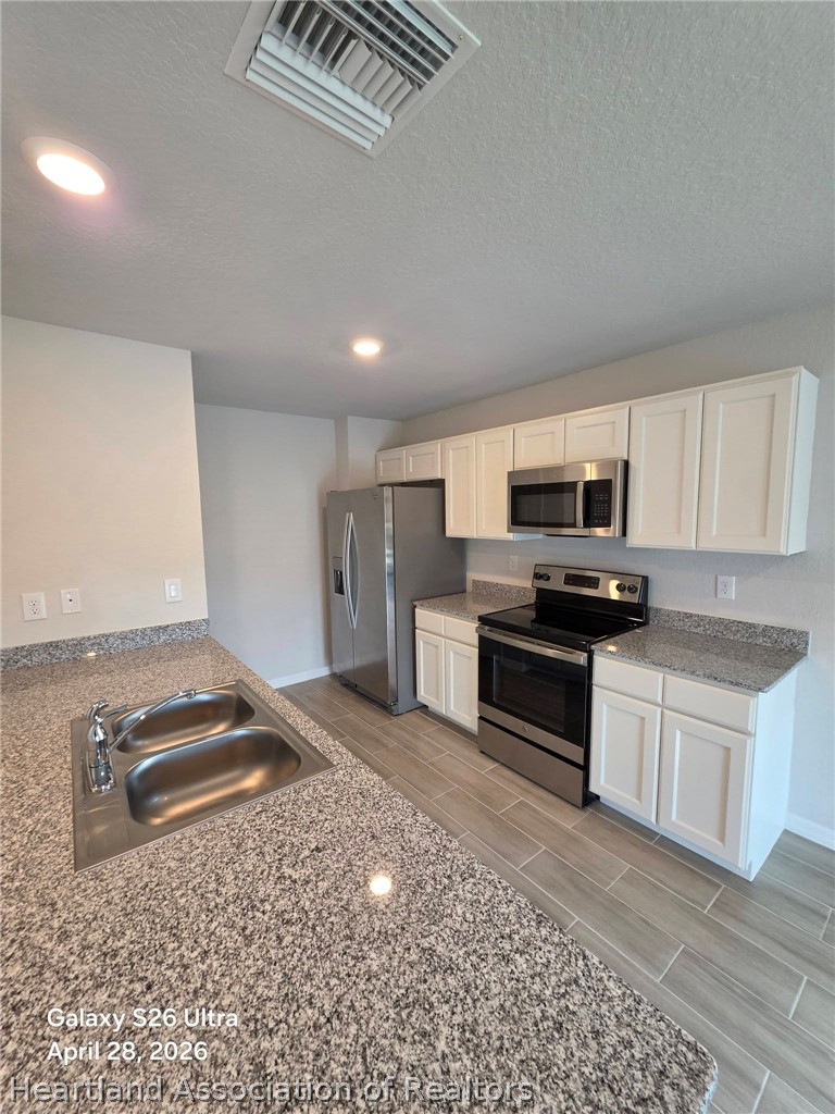 1613 Marble Street Sebring, FL 33870 - Photo 4 of 20 a kitchen with stainless steel appliances granite countertop a stove a sink and a refrigerator