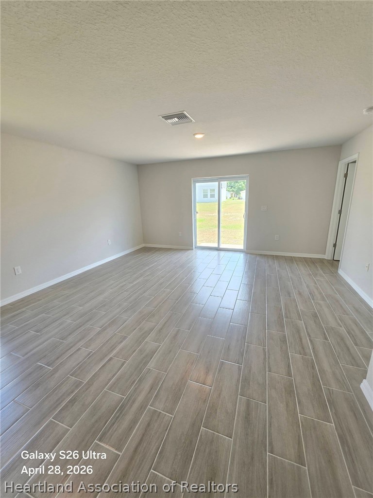 1613 Marble Street Sebring, FL 33870 - Photo 5 of 20 an empty room with wooden floor and windows