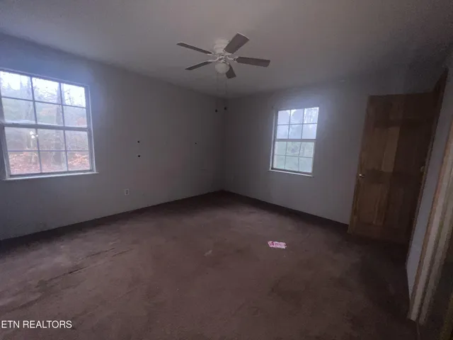 an empty room with a window and a ceiling fan