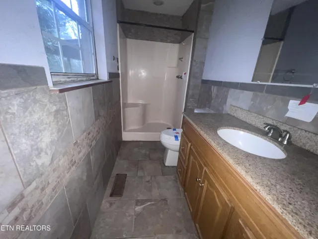 a bathroom with a granite countertop sink a toilet and a mirror