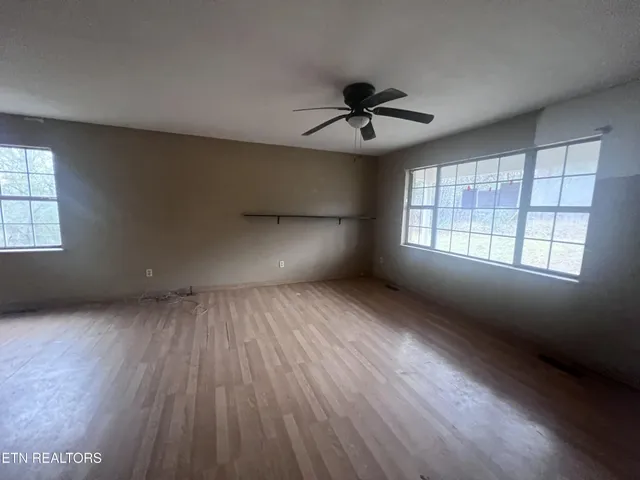 a view of an empty room with a window and wooden floor