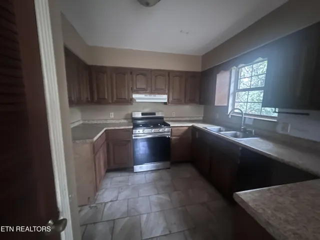 a kitchen with a sink a stove a refrigerator and a window