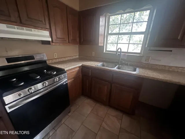 a kitchen with a sink stove top oven and cabinets