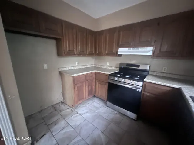 a kitchen with granite countertop a stove a sink and a refrigerator