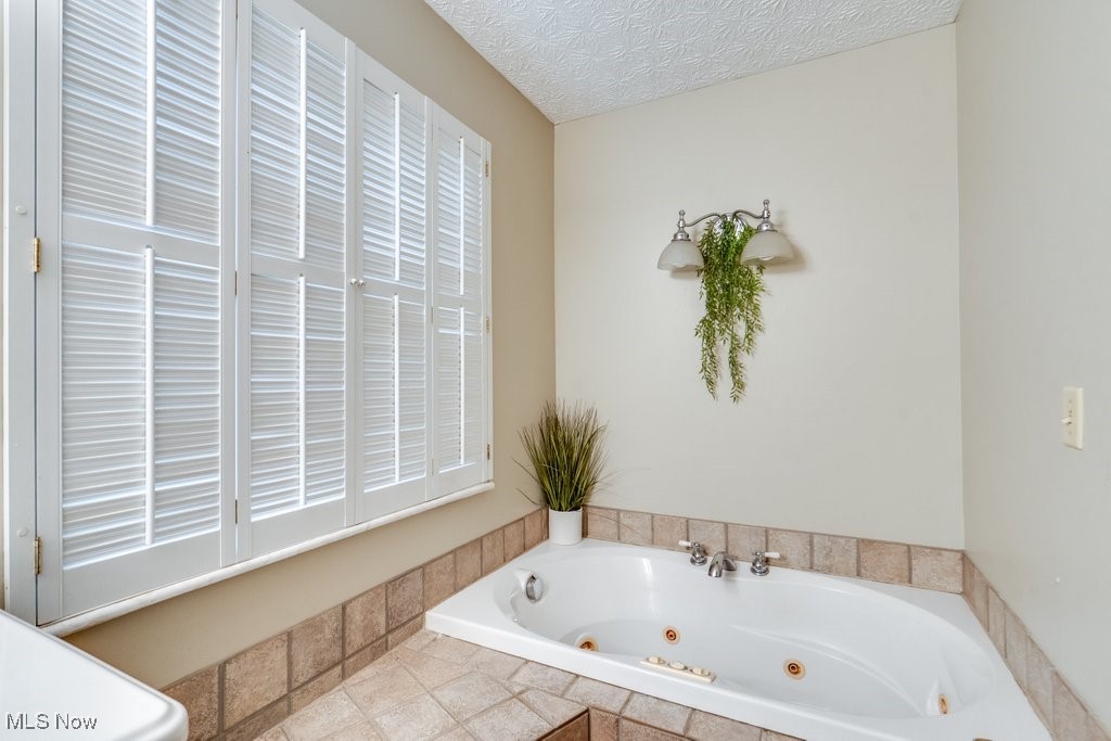 4100 Jade Road Northwest Carrollton, OH 44615 - Photo 29 of 37 Bathroom featuring a textured ceiling and a relaxing tiled tub