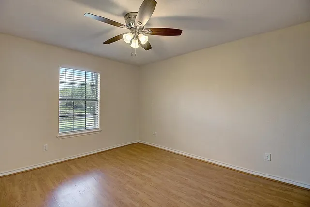 an empty room with a window and a fan