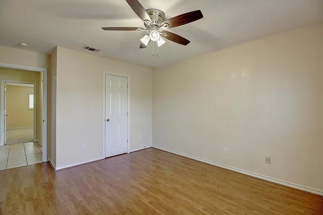 an empty room with a chandelier fan and windows
