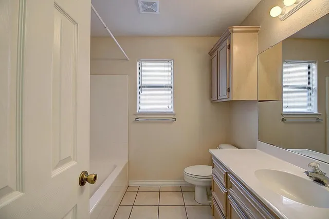 an empty room with a chandelier fan and windows