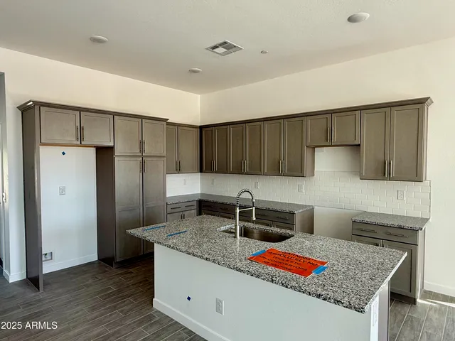 a kitchen with granite countertop a refrigerator and a stove top oven