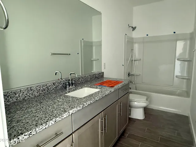a bathroom with a granite countertop sink a toilet and shower