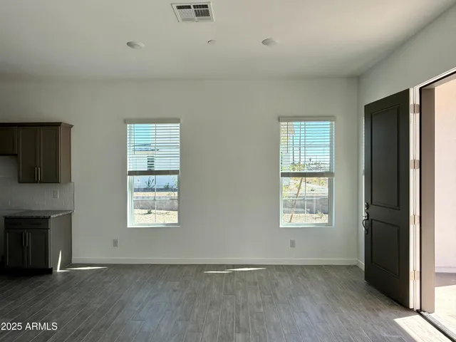an empty room with wooden floor a ceiling fan and windows