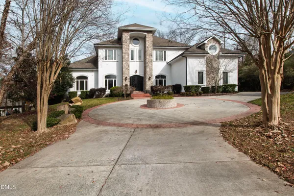 a view of a white house with large outdoor space and a tree