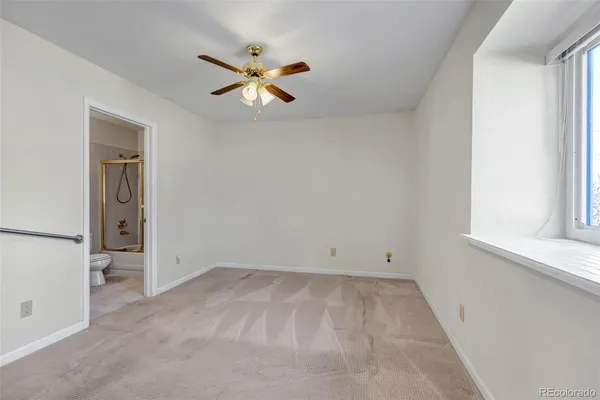 an empty room with windows and fan