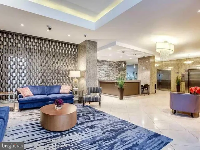 a lobby with a potted plant and a kitchen view