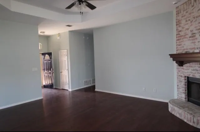 an empty room with wooden floor a fireplace and windows