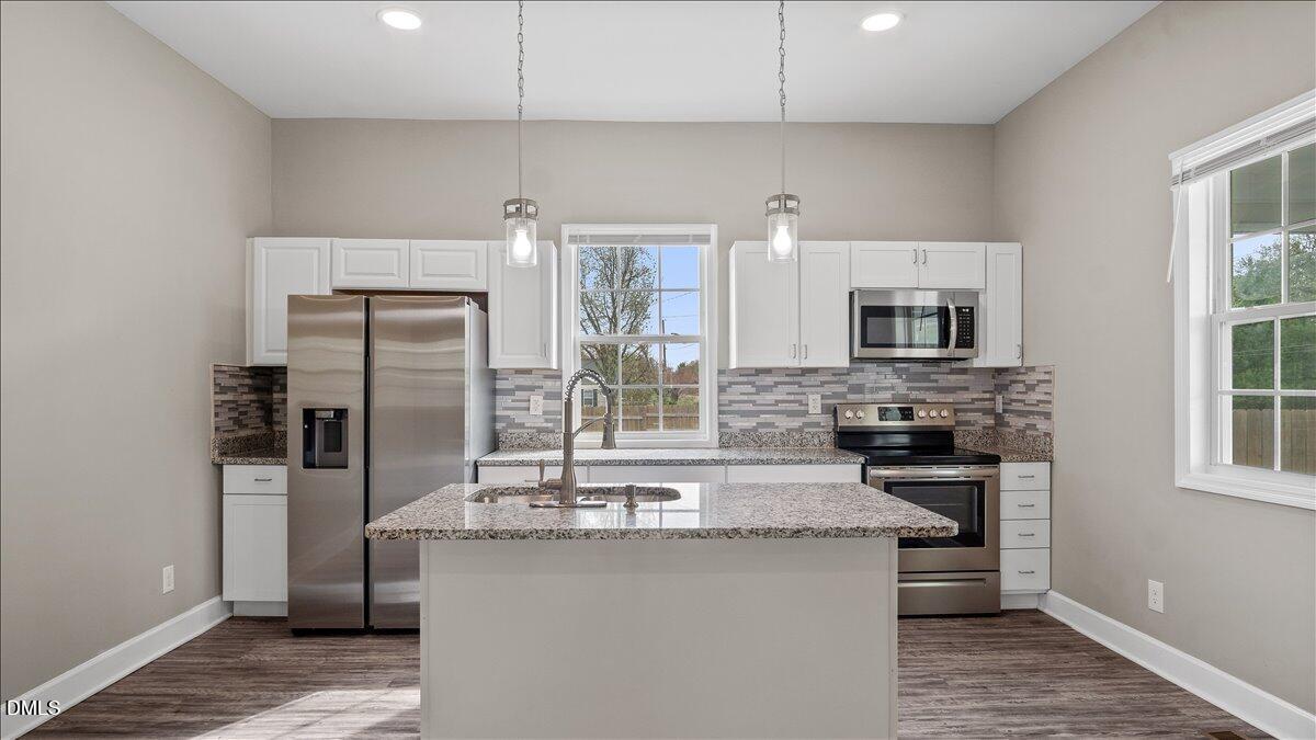 a kitchen with stainless steel appliances a sink stove refrigerator and cabinets
