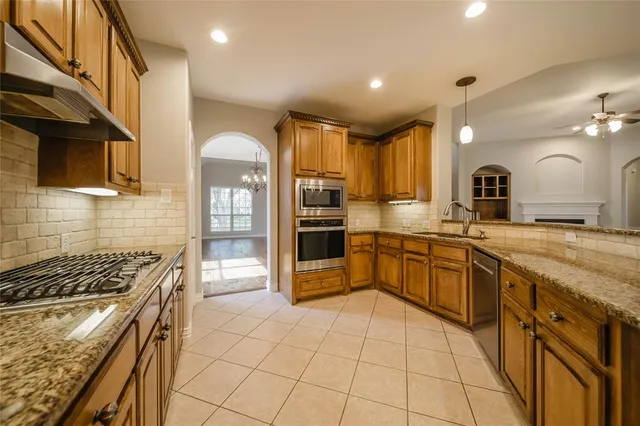 a kitchen with stainless steel appliances granite countertop a stove a sink and a refrigerator