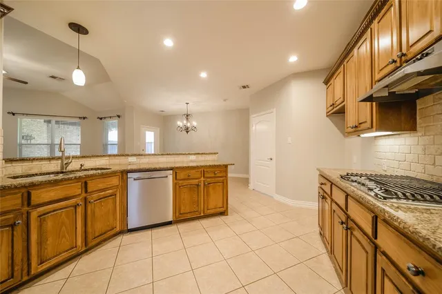 a kitchen with granite countertop a sink a counter top space and cabinets