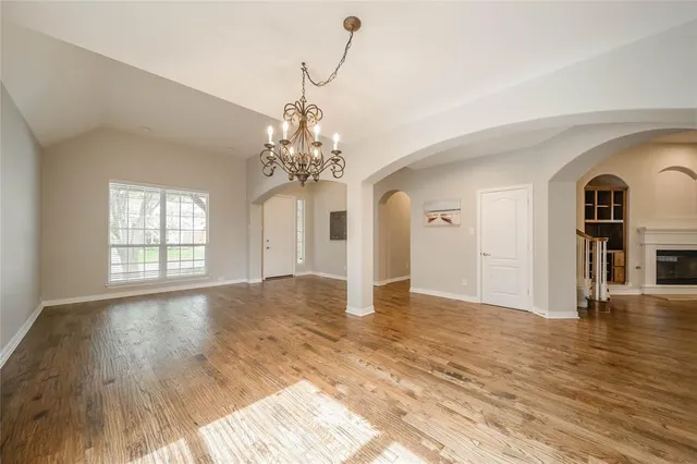 a view of a room with wooden floor chandelier and windows