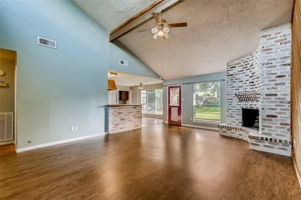 an empty room with wooden floor fireplace and windows