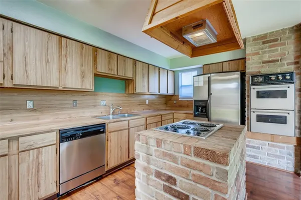 a kitchen with kitchen island granite countertop a sink stainless steel appliances and cabinets