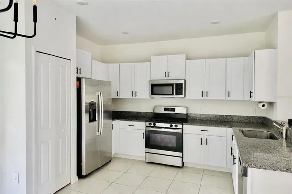 a kitchen with granite countertop white cabinets and white appliances