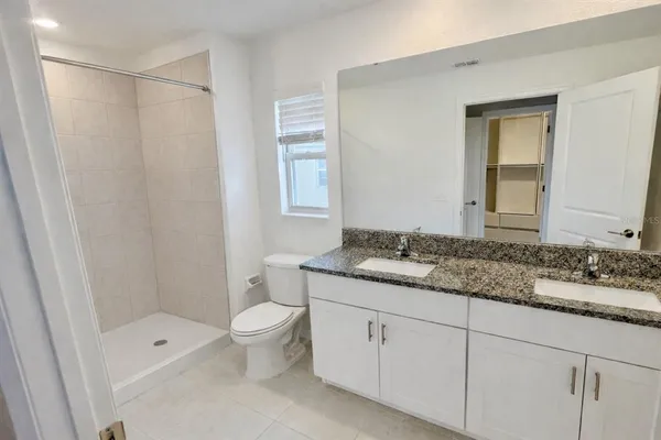 a bathroom with a granite countertop sink a toilet and shower