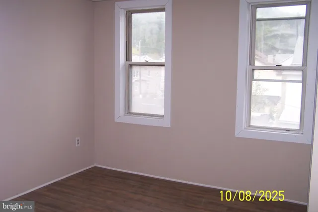 an empty room with wooden floor closet and windows