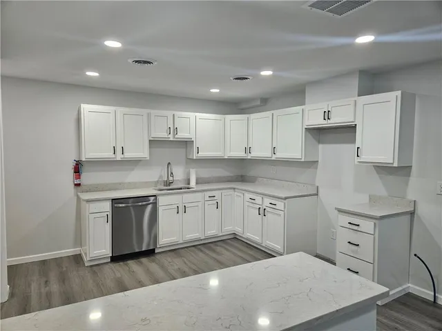 a kitchen with granite countertop a sink a stove a refrigerator and white cabinets
