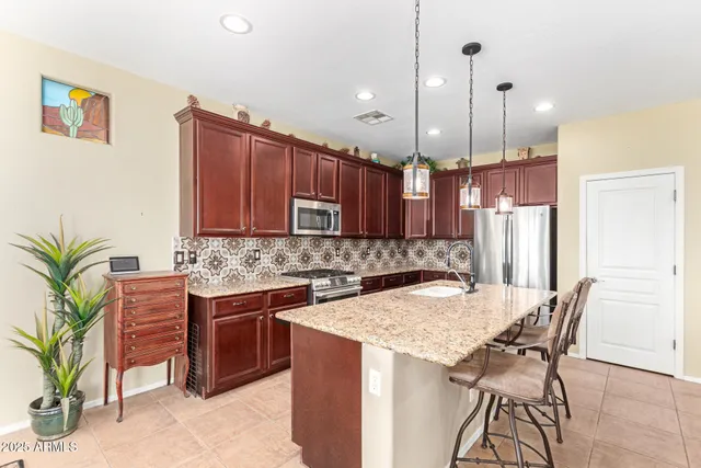 a kitchen with stainless steel appliances granite countertop a sink a stove and a wooden floors