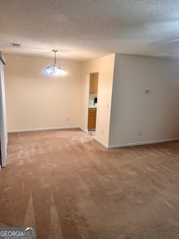 a view of an empty room with a chandelier fan