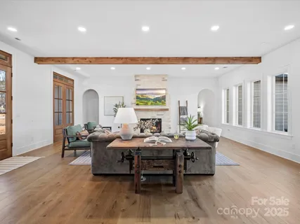 a living room with furniture a large window and wooden floor