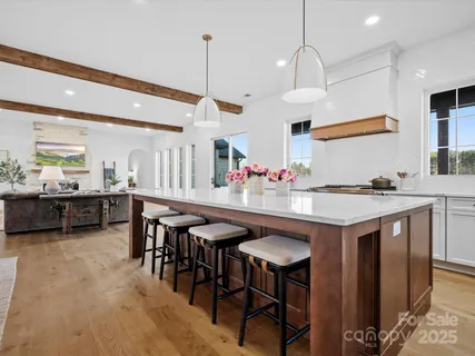 a kitchen with stainless steel appliances kitchen island granite countertop a table chairs sink and cabinets