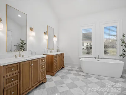 a spacious bathroom with a tub sink double vanity granite and mirror