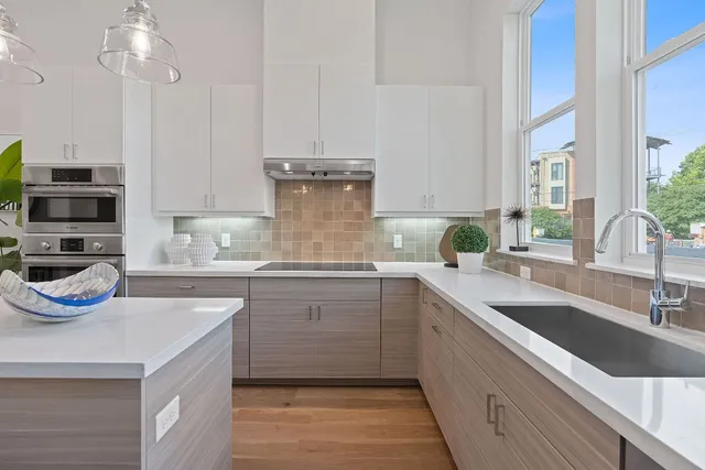 a kitchen with kitchen island granite countertop a sink and a stove top oven